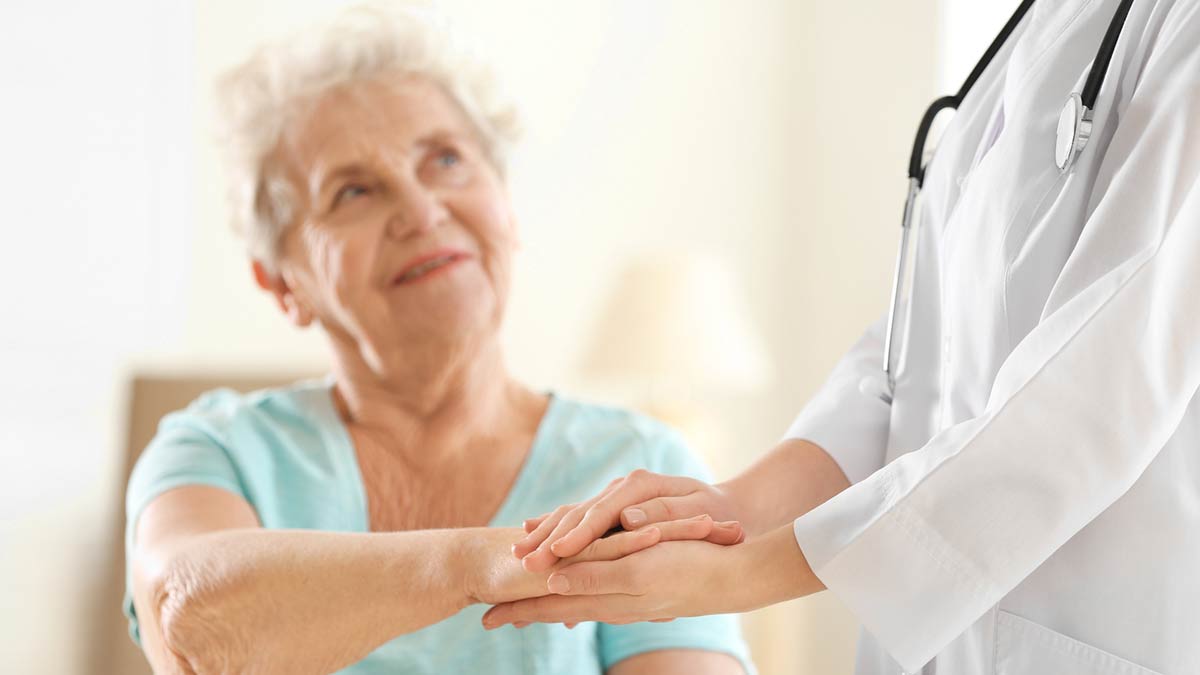 An elderly woman comforted by a doctor.