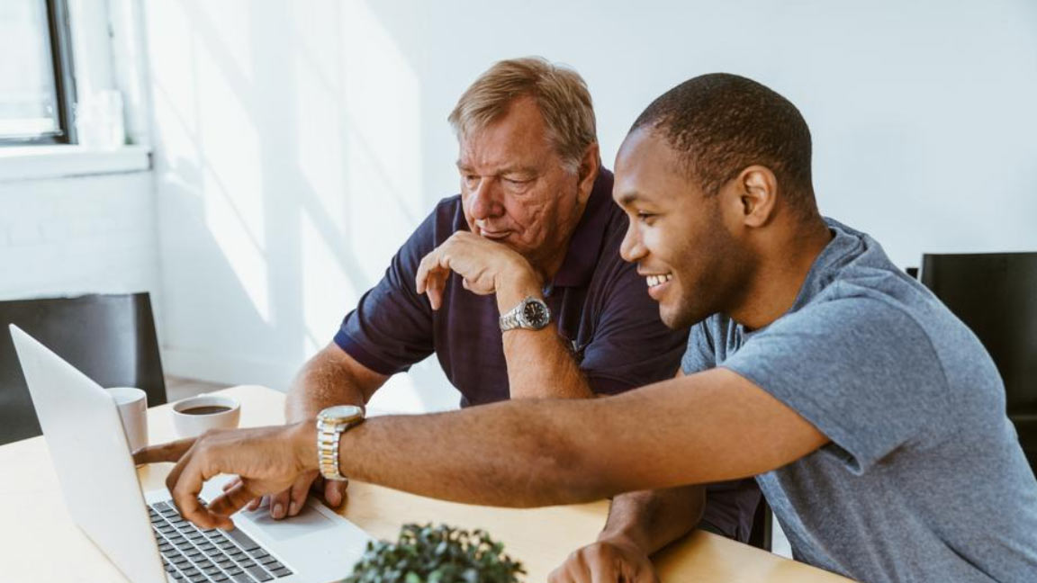 Two men on a computer looking for Medicaid information