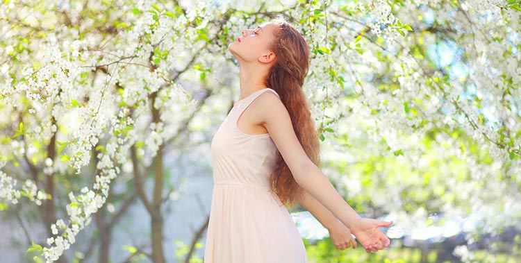 a young woman smelling tree blossoms