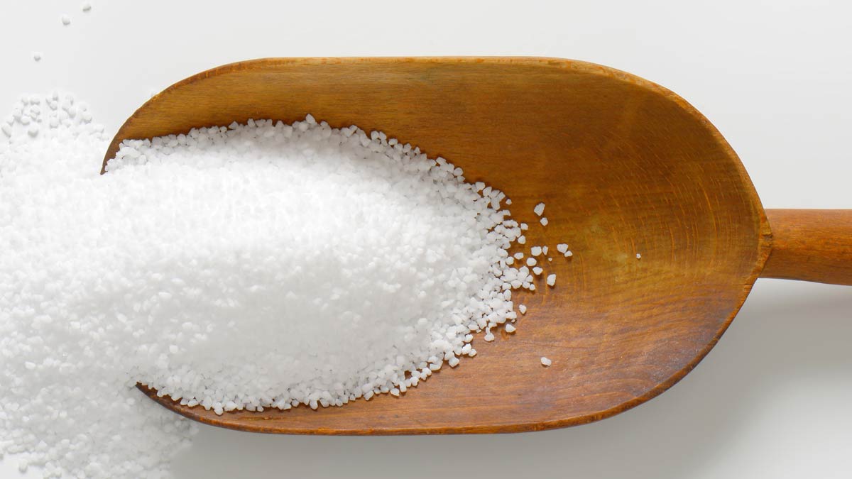 A large, wooden scoop of salt for article "The Truth About Salt"