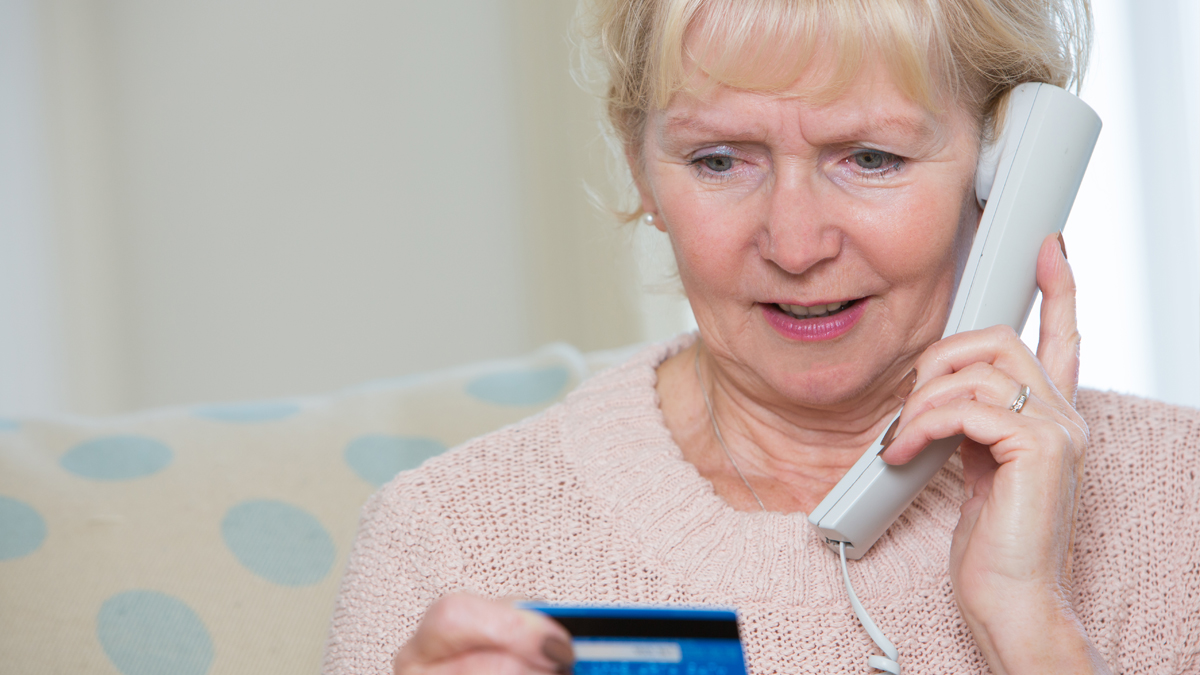 A woman on the phone giving credit card information to scammers