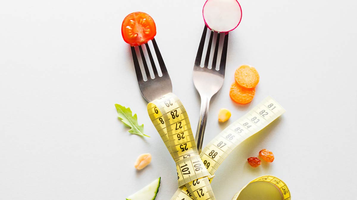 Diets: two forks and some healthy foods with a tape measure.