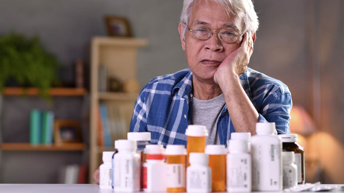 This senior gentleman almost seems depressed by the sheer number of medication bottles he has to deal with.