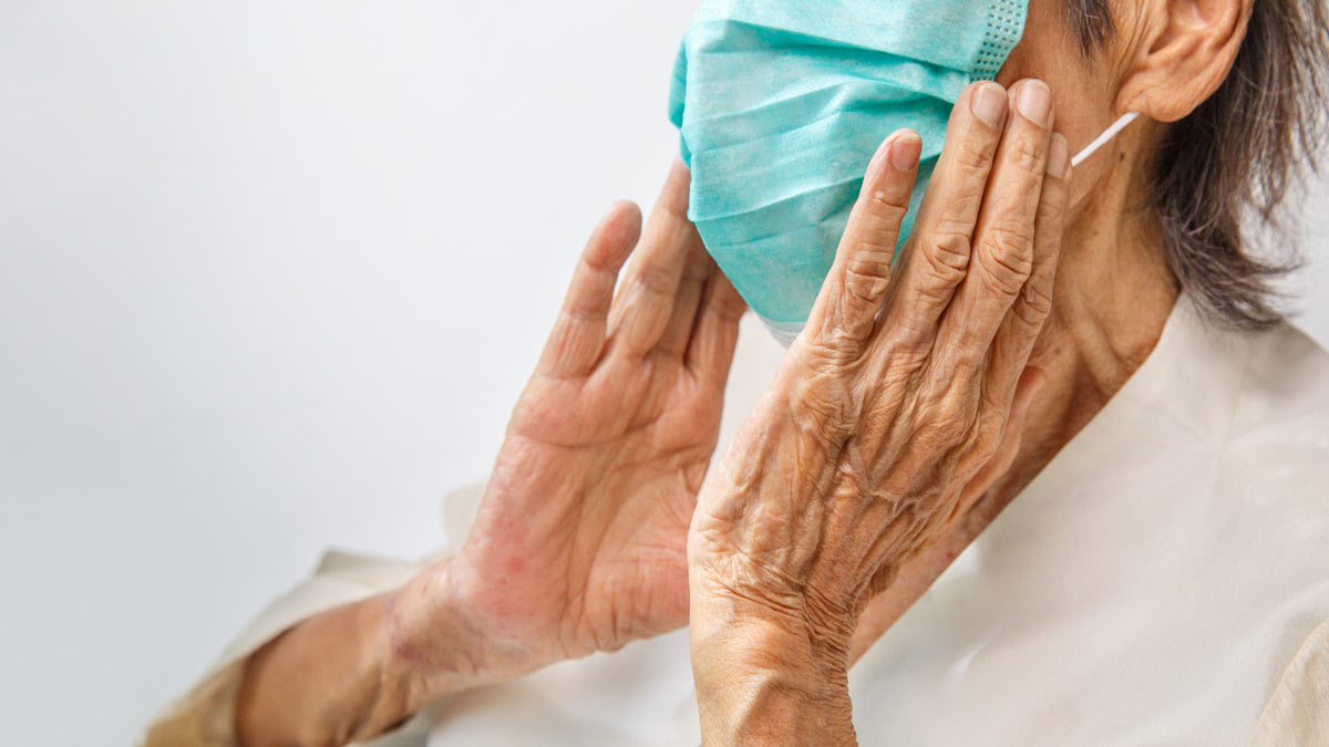 An elderly person uses a face mask for protection.