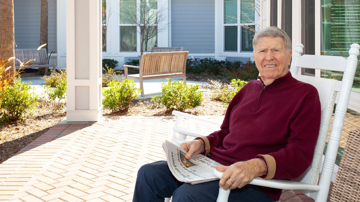 An older gentleman with his newspaper outdoors.