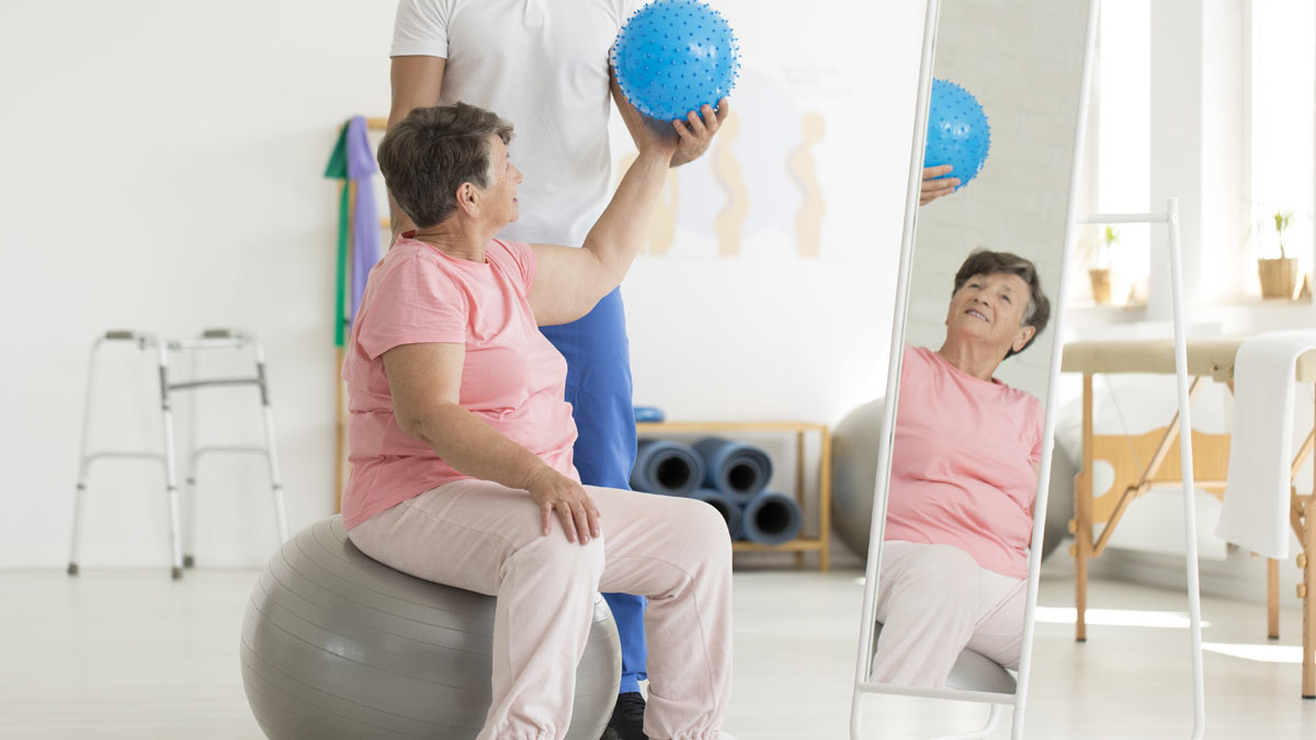 A woman on an exercise ball doing physical therapy exercises.