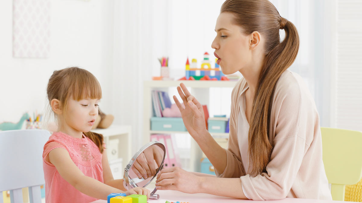 A speech therapist working with a young girl.