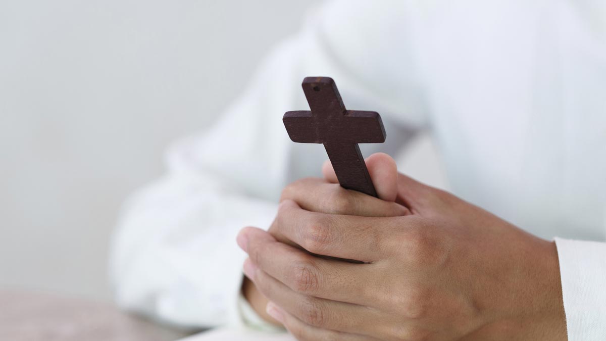 Photo of a man holding a cross for the Hospital Chaplains article.