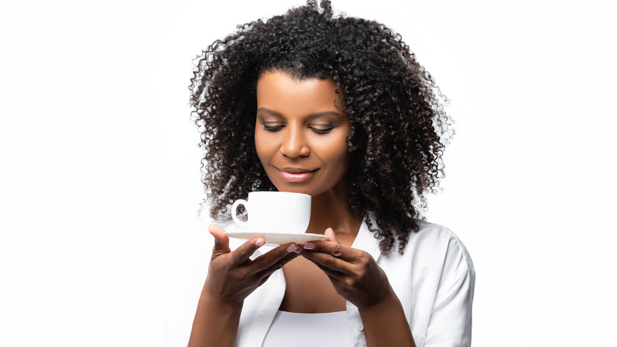 Woman smelling cup of coffee