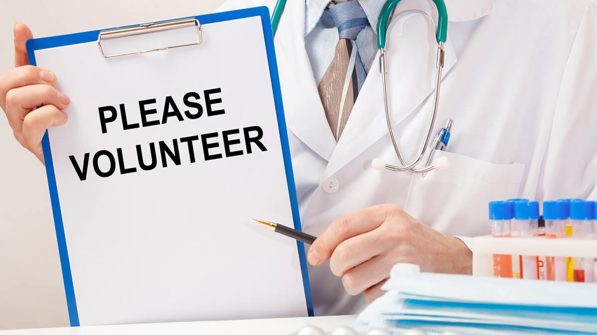 Doctor holding Please Volunteer sign