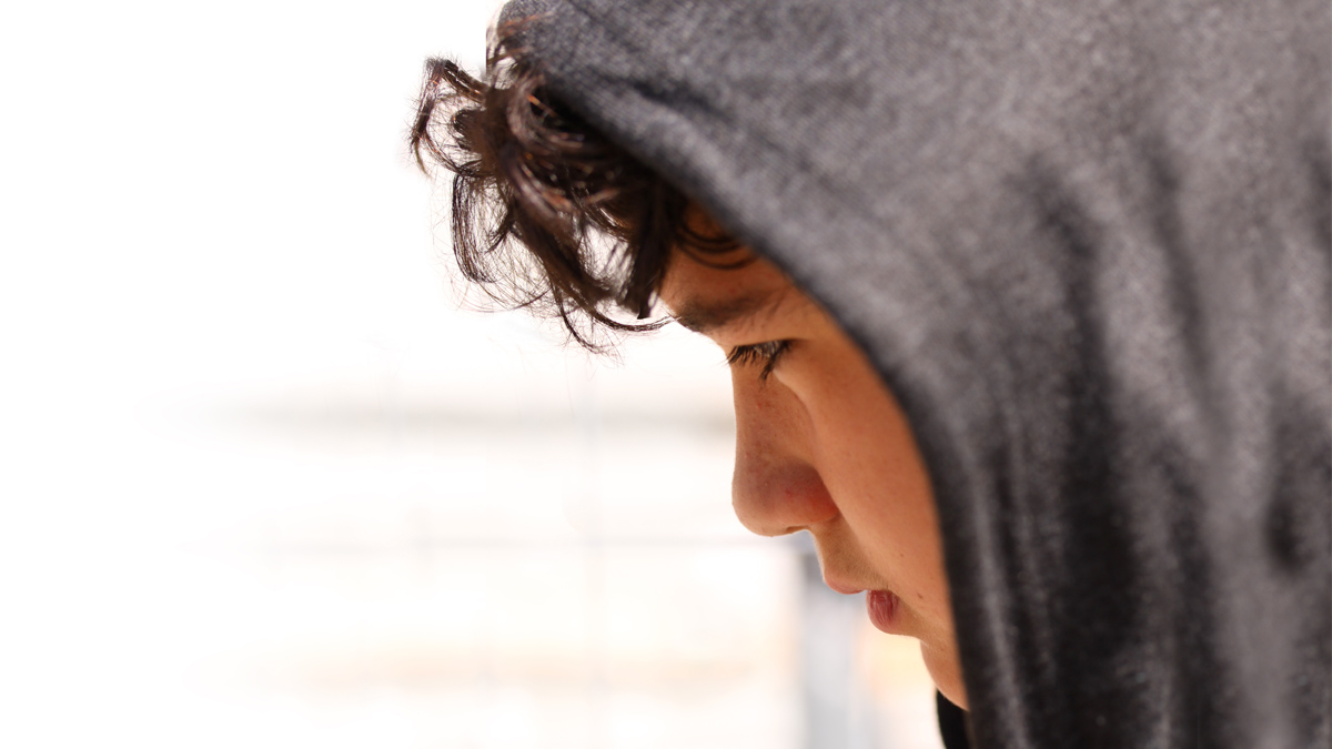 Boy with hood up looking stressed in school