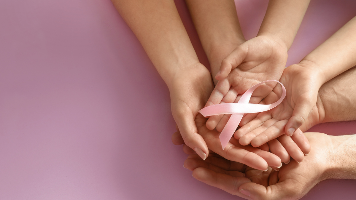 Hands together holding the pink Breast Cancer ribbbon