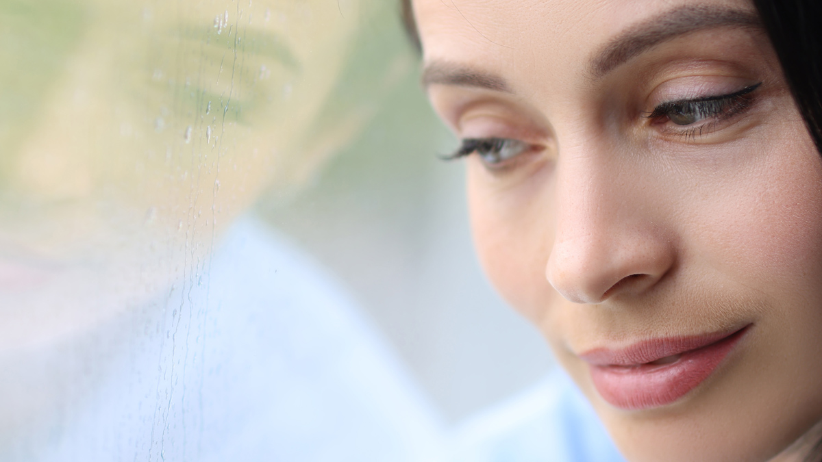 Photo of woman who is looking out the window at a reflection of herself