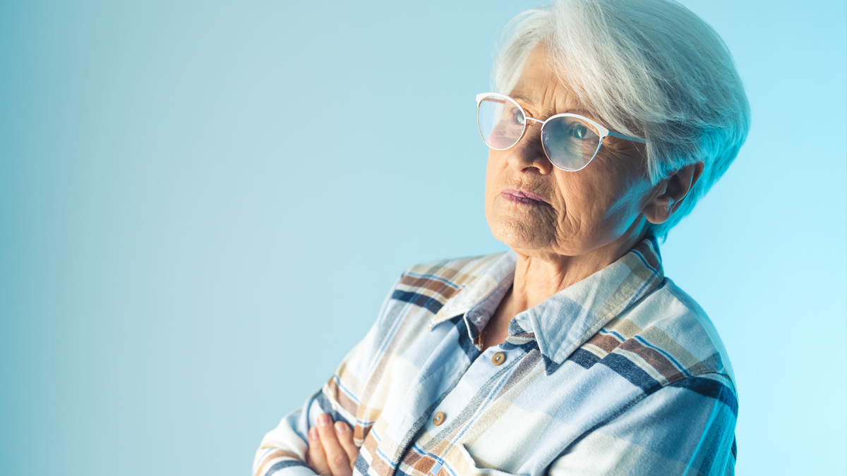 Photo of an older woman with her arms crossed looking in the distance