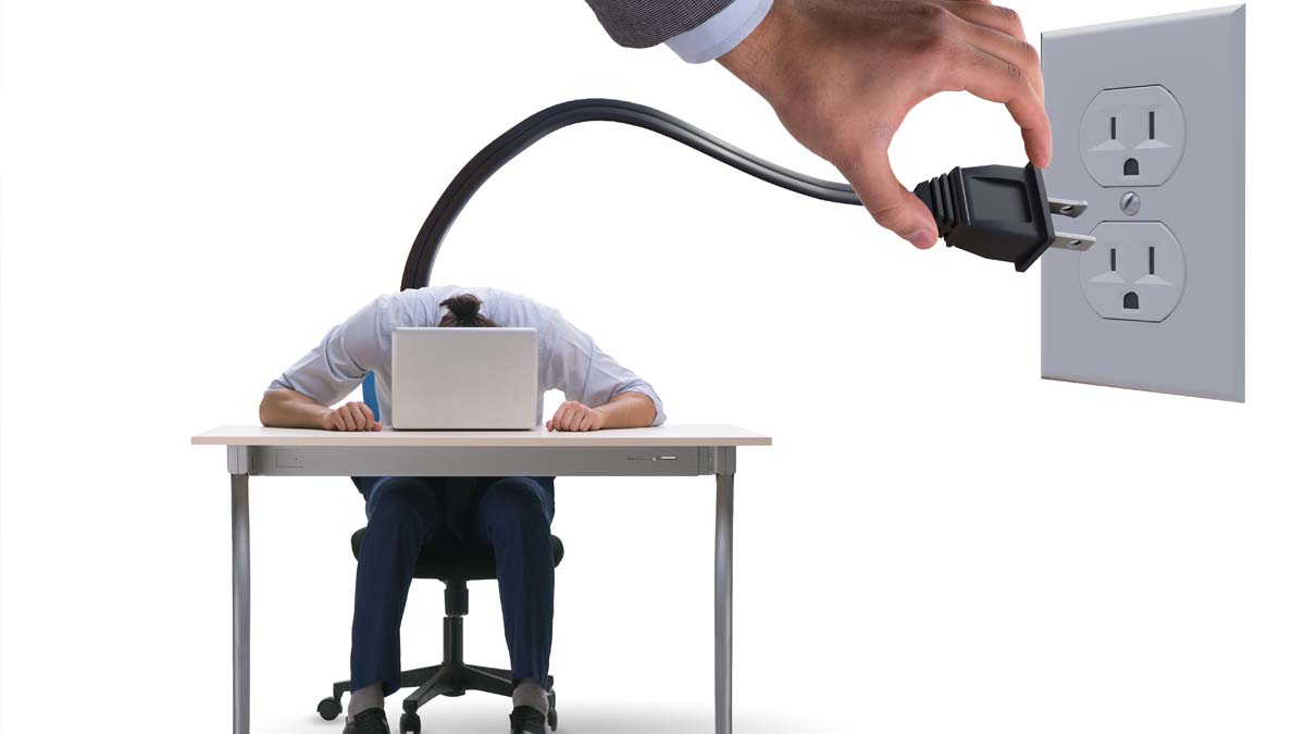 Graphic of a person with their head down at a desk with a power cord plugged in