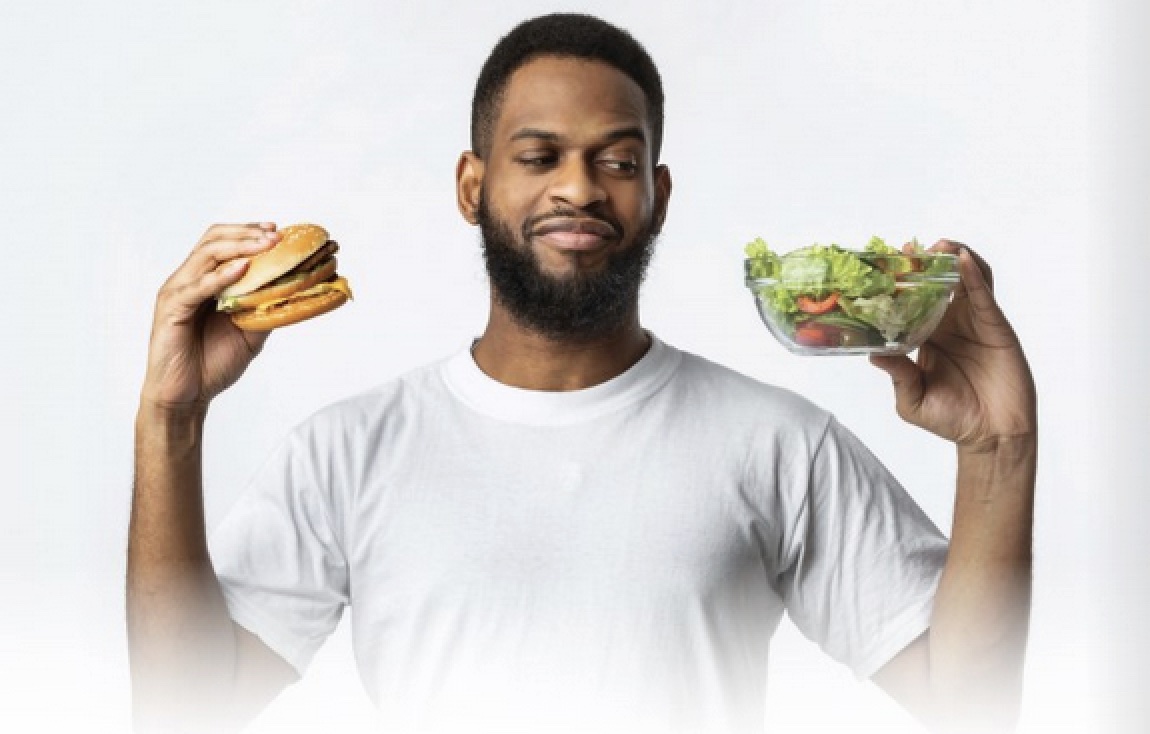 Photo of a man who has a salad in one hand and a burger in the other